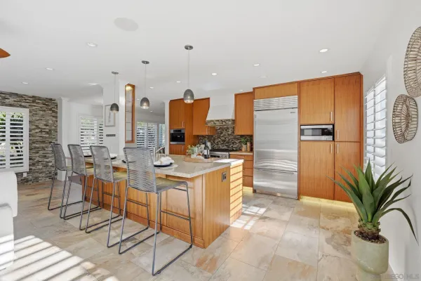 a kitchen with stainless steel appliances kitchen island granite countertop a refrigerator a stove and a dining table with wooden floor