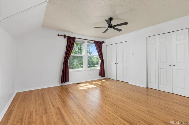 a view of empty room with wooden floor and fan
