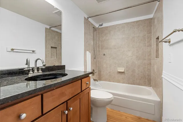 a bathroom with a granite countertop sink a toilet a mirror and shower