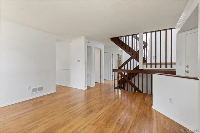 a view of empty room with wooden floor and fan