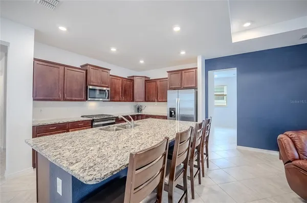 a kitchen with a stove a sink a refrigerator and chairs