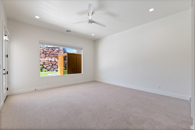 1192 East Corral Way Washington, UT 84780 - Photo 25 of 81 Carpeted interior space featuring a ceiling fan with integrated lighting, recessed ceiling lights, and a window overlooking a rock wall and artificial turf area