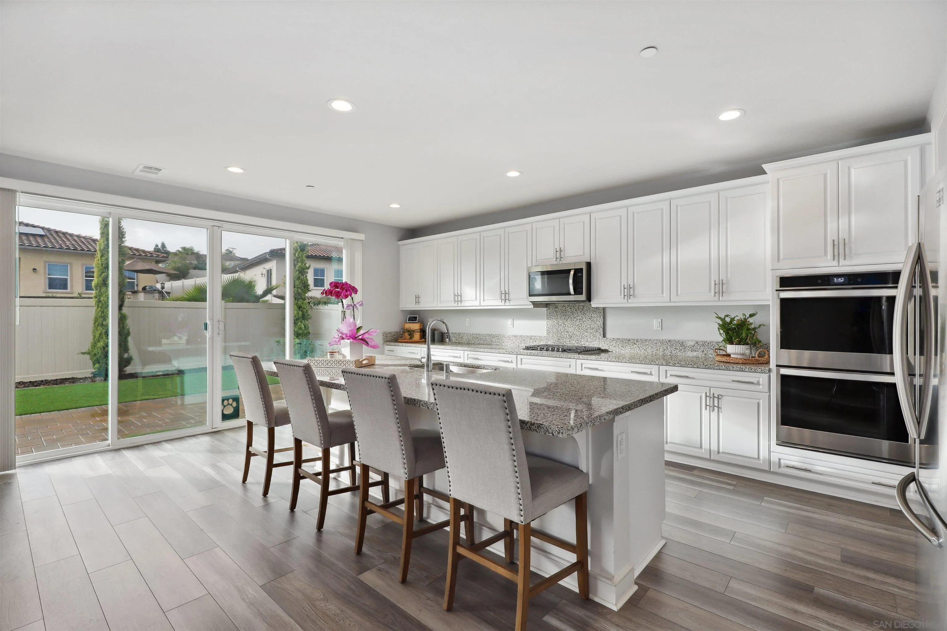 1294 Palomar Circle Escondido, CA 92027 - Photo 12 of 41 a kitchen with stainless steel appliances granite countertop a stove top oven a sink dishwasher a dining table and chairs with wooden floor