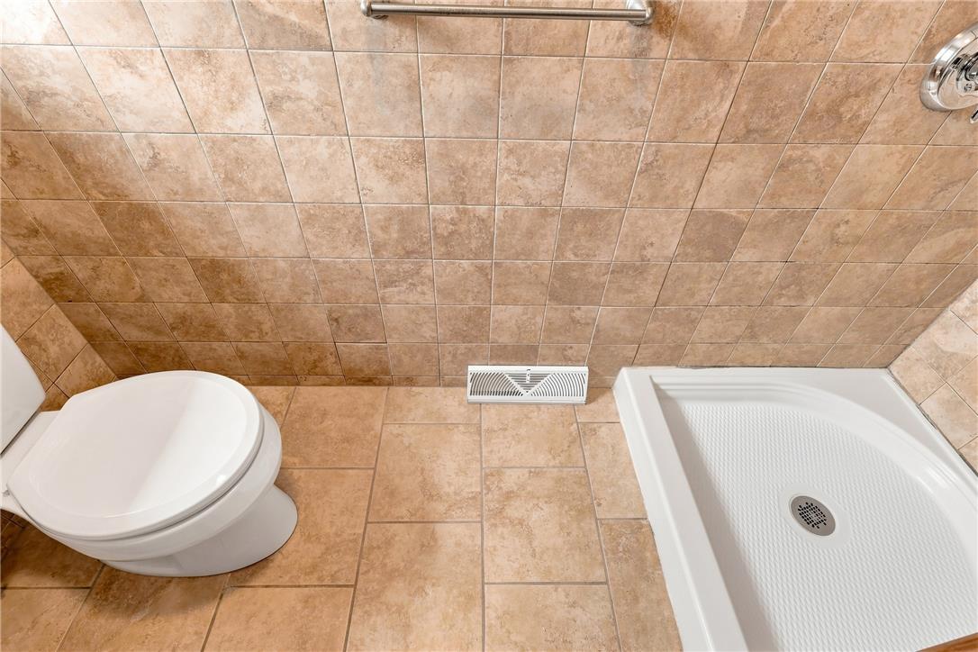 6090 Stone Post Road Bath, PA 18014 - Photo 30 of 57 A well-appointed bathroom featuring a clean commode and a compact shower stall with tile flooring.