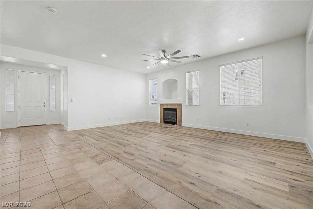 835 Entrada Ridge Avenue Henderson, NV 89012 - Photo 3 of 34 A well-lit living area features modern wood flooring and a cozy fireplace, perfect for relaxation.