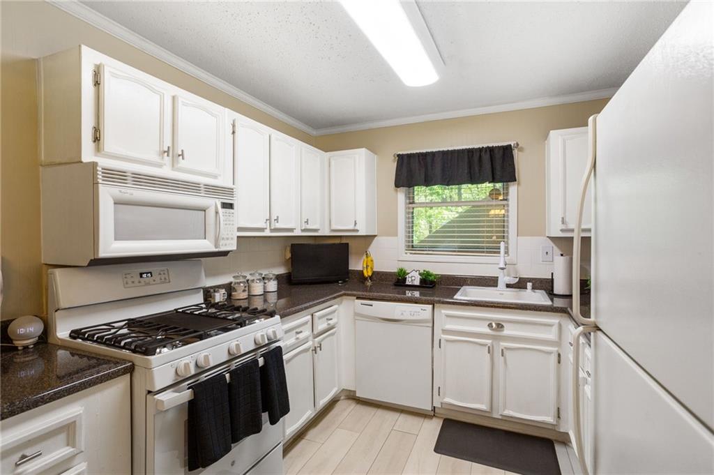 306 Countryside Place Smyrna, GA 30080 - Photo 11 of 35 a kitchen with white cabinets appliances a sink and a window