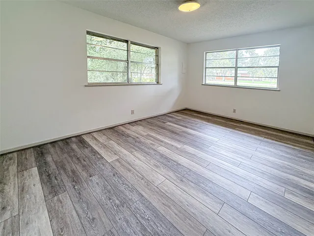 a view of empty room with wooden floor and windows
