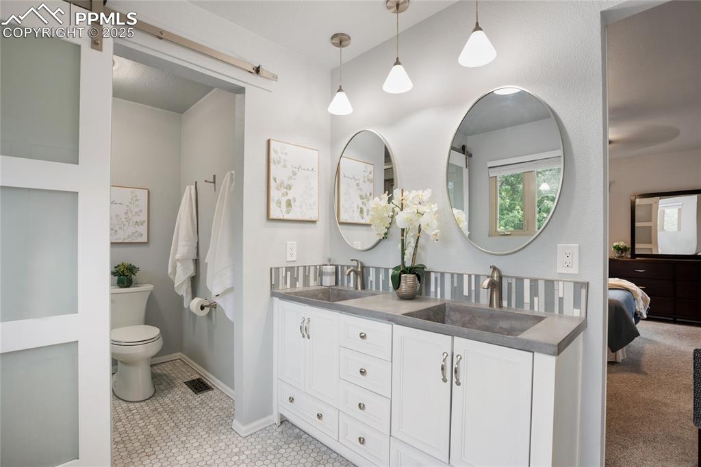 3004 Springlake Circle East Colorado Springs, CO 80906 - Photo 25 of 50 a bathroom with double vanity sinks a toilet a large mirror and vanity