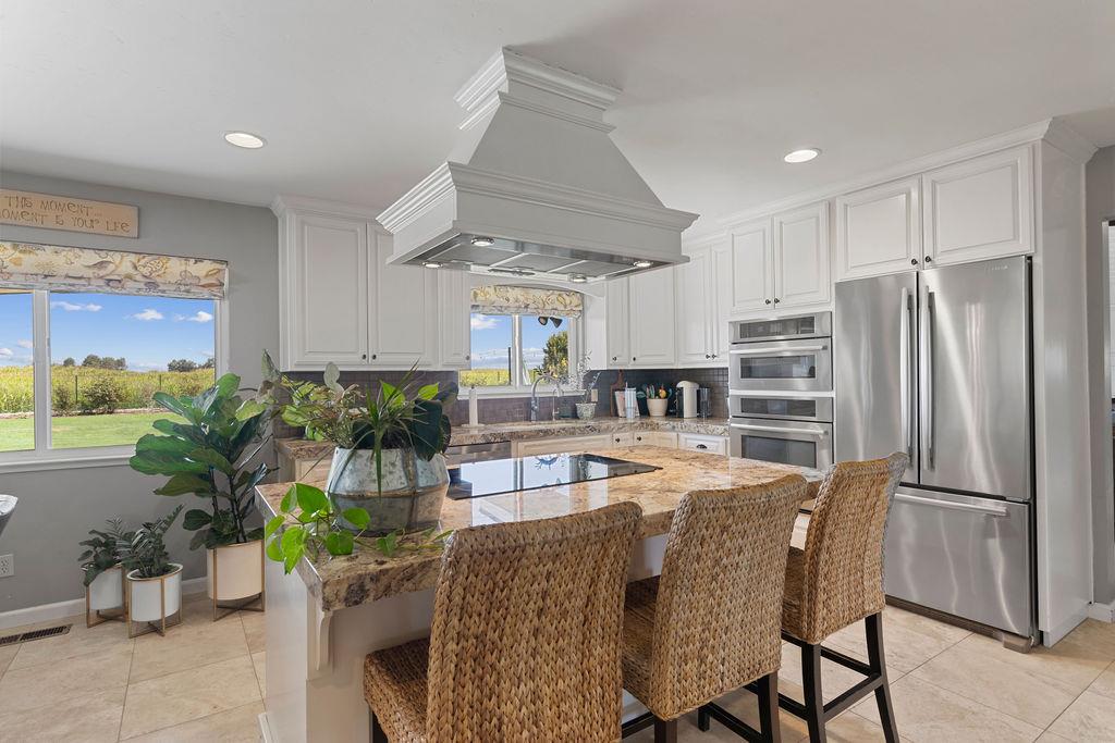 4930 South Faith Home Road Turlock, CA 95380 - Photo 13 of 69 kitchen featuring Jenn-Air stainless steel appliances, updated cabinetry, a kitchen breakfast bar, a kitchen island, and decorative backsplash