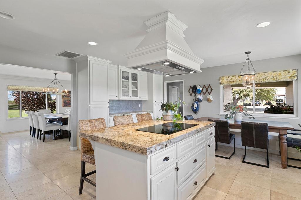 4930 South Faith Home Road Turlock, CA 95380 - Photo 15 of 69 kitchen featuring hanging lights, a breakfast bar, white cabinetry, glass insert cabinets, and black electric cooktop