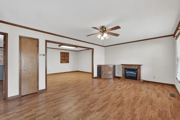 a view of an empty room with a window and wooden floor
