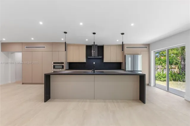 a large kitchen with stainless steel appliances kitchen island granite countertop a refrigerator a sink a stove a microwave and white cabinets