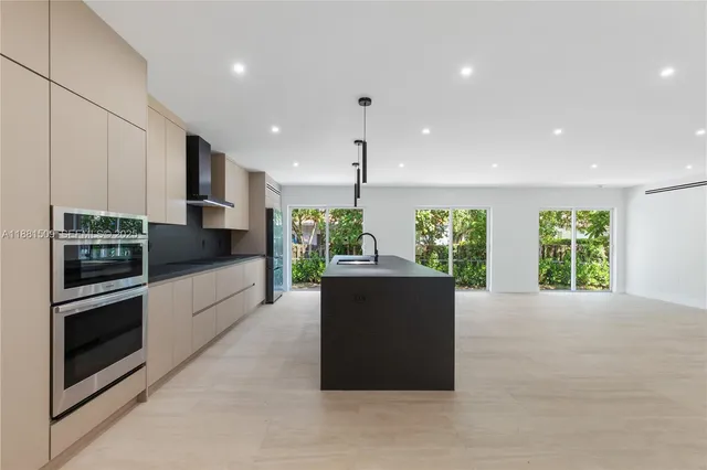 a kitchen with stainless steel appliances kitchen island granite countertop a refrigerator a sink a stove and oven