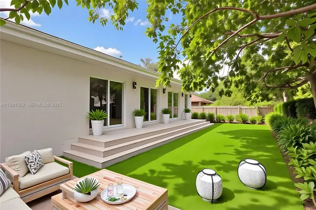 a view of a white house with a big yard and large trees