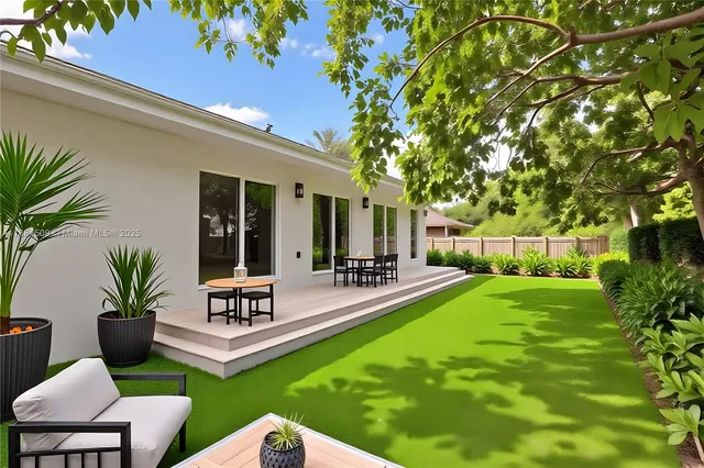 a view of a white house in front of a yard with potted plants