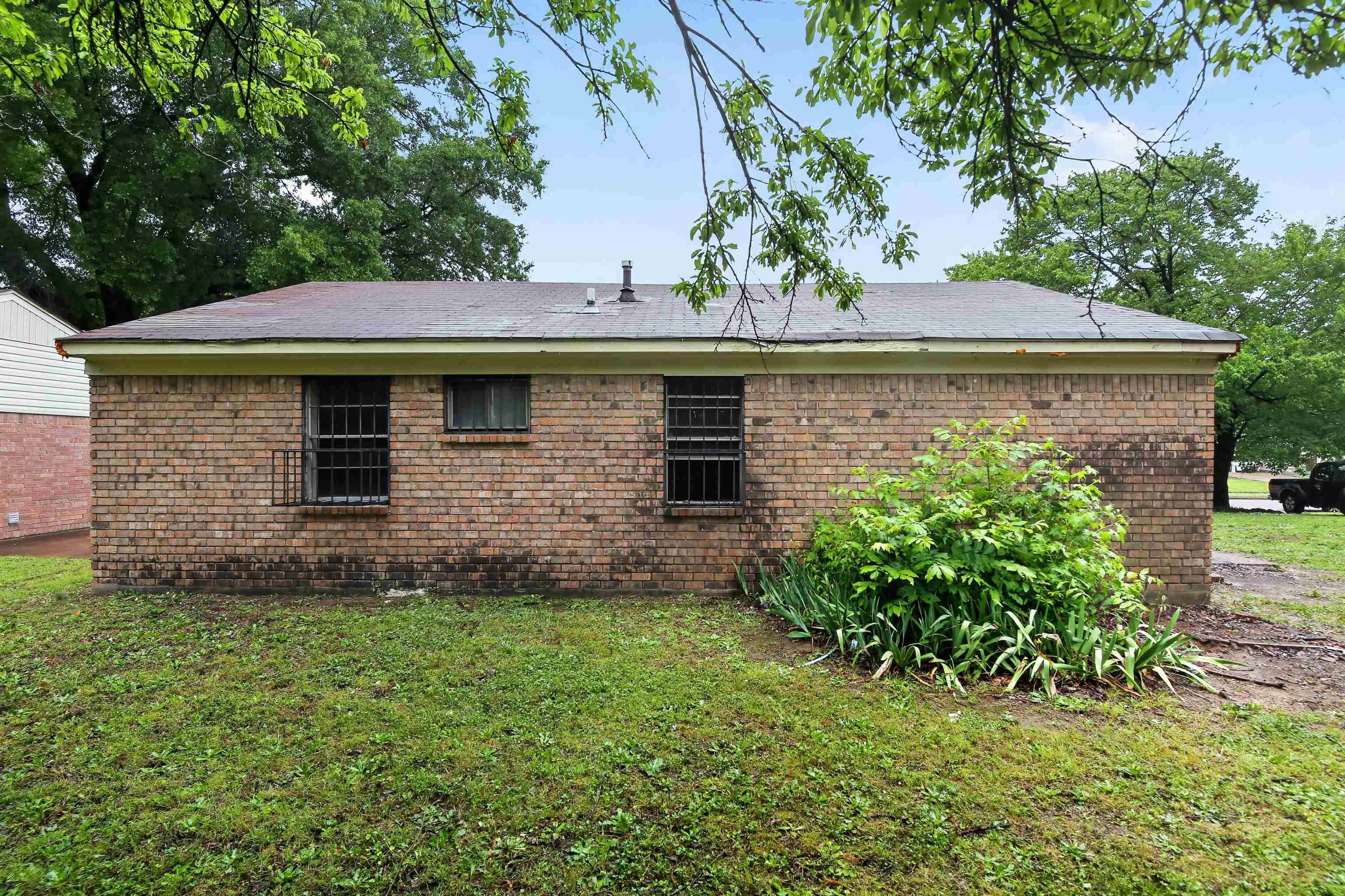 3451 Birdsong Ferry Road Memphis, TN 38118 - Photo 3 of 27 Brick exterior with a low-slope roofline, featuring security bars on windows and established landscaping