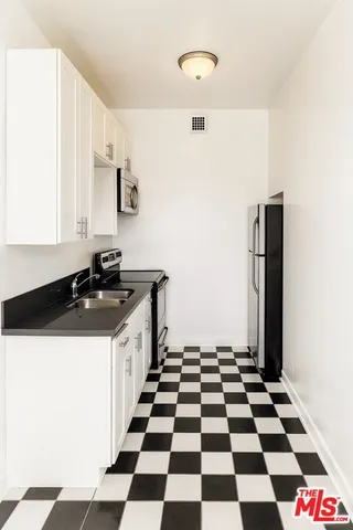 a kitchen with a sink a refrigerator and cabinets