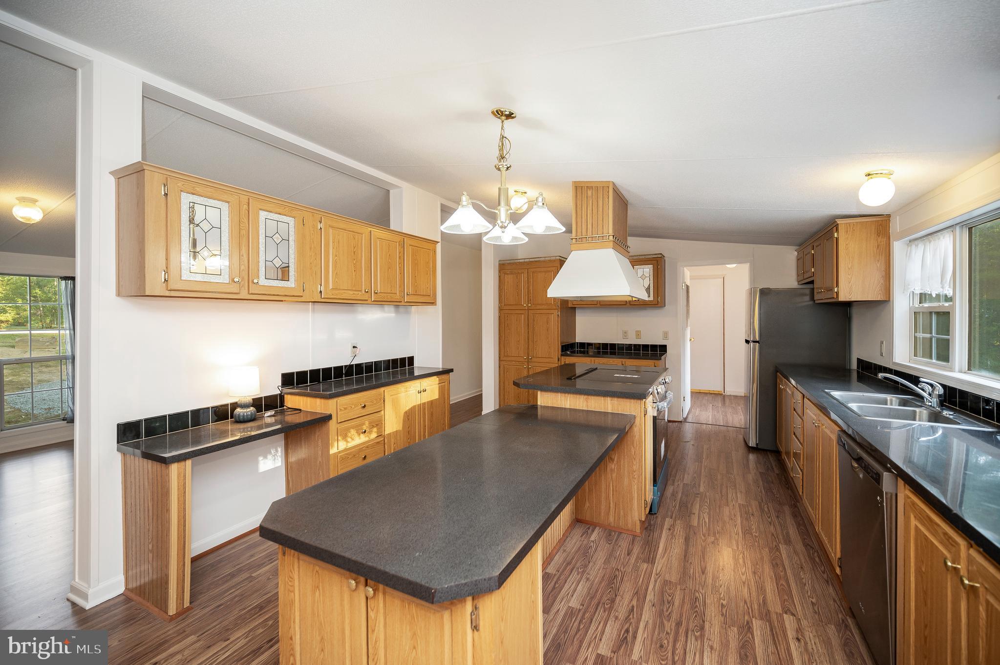 9863 Red Hill Road Spotsylvania, VA 22553 - Photo 18 of 53 a kitchen with a stove a refrigerator a sink dishwasher with a dining table and chairs with wooden floor