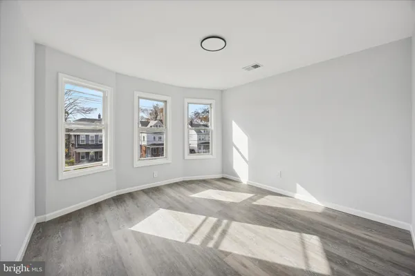 a view of an empty room with a window and wooden floor