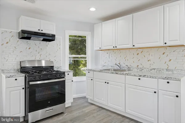 a kitchen with granite countertop white cabinets and stainless steel appliances