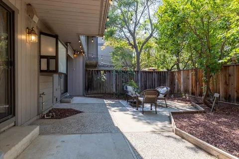 a view of a patio with table and chairs with wooden fence and a large tree