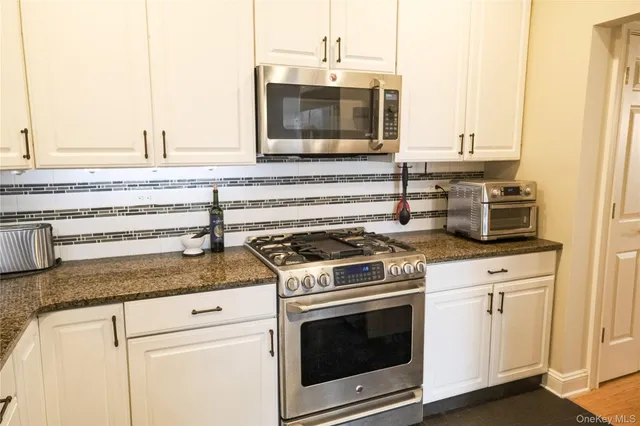 a kitchen with granite countertop a stove and a microwave