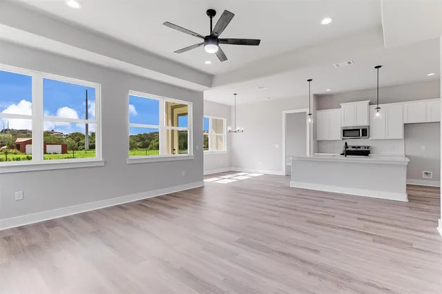 a view of an empty room with a kitchen and wooden floor