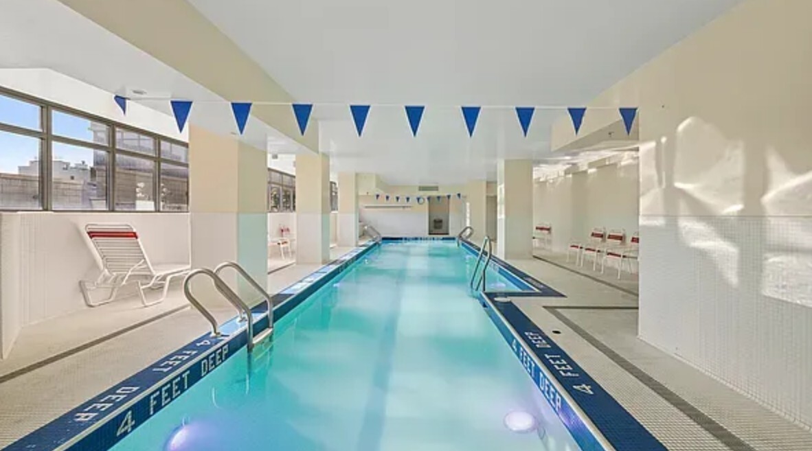 1485 5th Avenue, Unit 13A Manhattan, NY 10035 - Photo 10 of 16 a hallway with a lots of white furniture and a chandelier