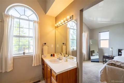 a en suite bathroom with a granite countertop sink a large mirror and a bathtub
