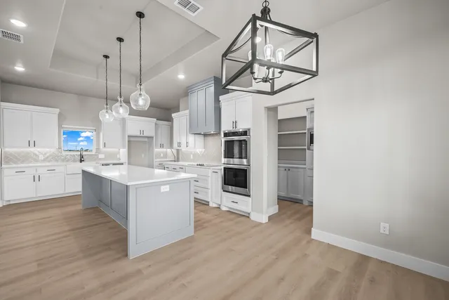 a kitchen with cabinets appliances and a chandelier