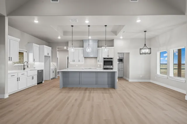 a large kitchen with lots of counter space a sink appliances and cabinets