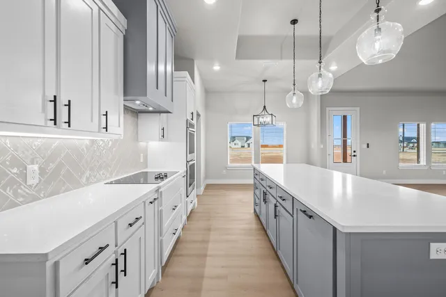 a large kitchen with kitchen island a large island wooden floor stainless steel appliances and a chandelier