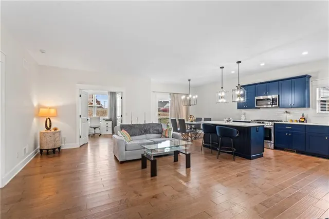 a large living room with stainless steel appliances kitchen island granite countertop lots of furniture and a wooden floors