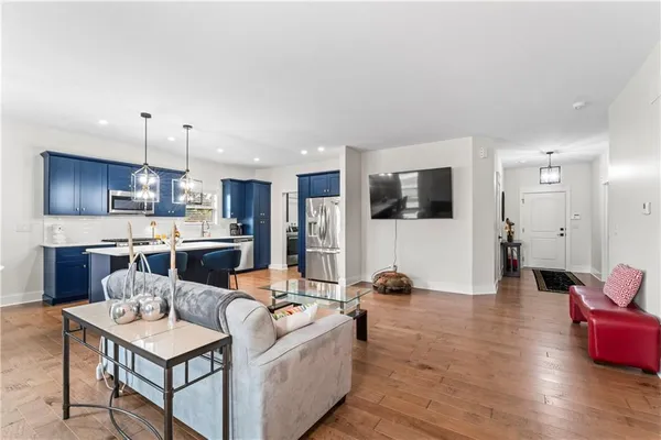 a living room with stainless steel appliances kitchen island granite countertop furniture a rug a kitchen island a stove and a wooden floors