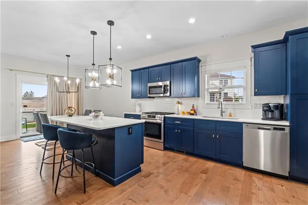 a kitchen with stainless steel appliances granite countertop wooden cabinets a sink a stove a dining table and chairs