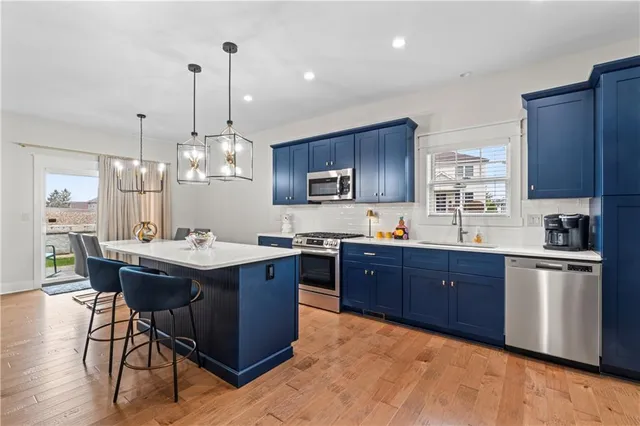 a kitchen with stainless steel appliances granite countertop wooden cabinets a sink a stove a dining table and chairs