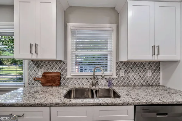 a kitchen with granite countertop a sink and a white wooden cabinets