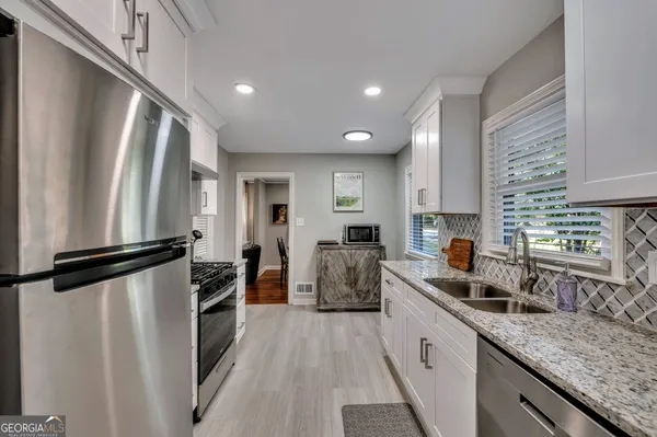 a kitchen with white cabinets and stainless steel appliances