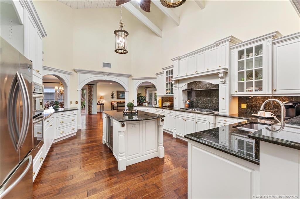 3192 Southeast Fairway West Stuart, FL 34997 - Photo 16 of 76 a kitchen with stainless steel appliances granite countertop a stove top oven a sink dishwasher a refrigerator and cabinets with wooden floor