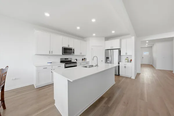 a kitchen with stainless steel appliances a refrigerator a stove top oven a sink dishwasher and a refrigerator with wooden floor