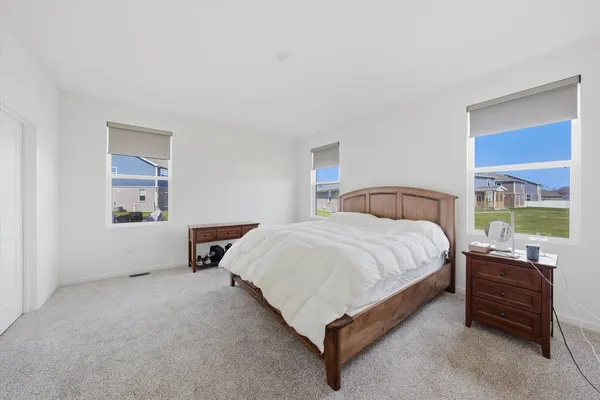 a spacious bedroom with a bed and wooden floor