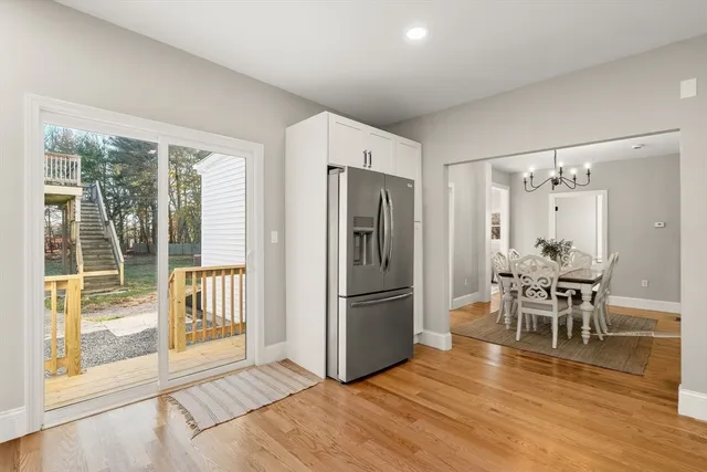 a kitchen with stainless steel appliances granite countertop a refrigerator a stove a dining table and chairs with wooden floor