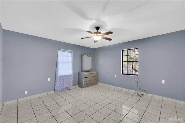 a view of an empty room with a window and a chandelier fan