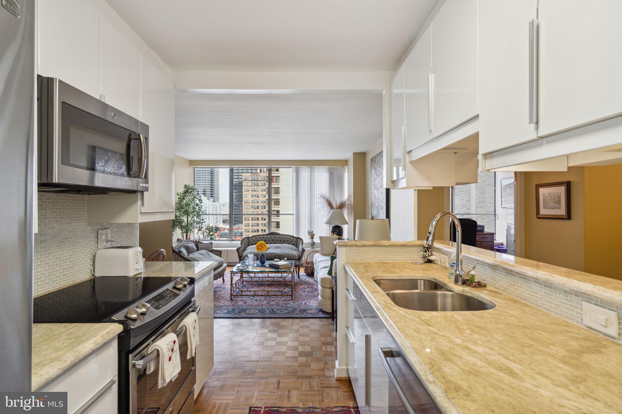 224-30 West Rittenhouse Square, Unit 1201 Philadelphia, PA 19103 - Photo 15 of 34 a kitchen with granite countertop a sink a stove top oven a dining table and chairs