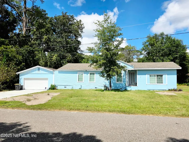 a front view of a house with a garden and trees