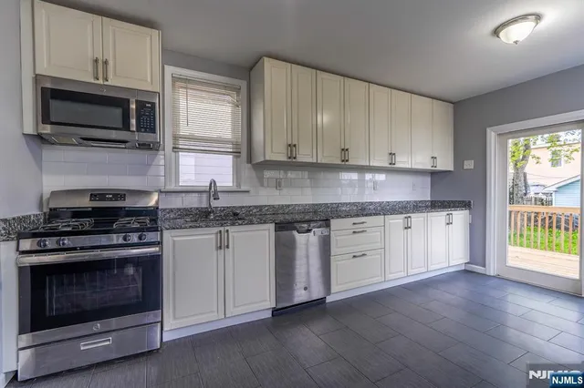 a kitchen with granite countertop white cabinets stainless steel appliances and window