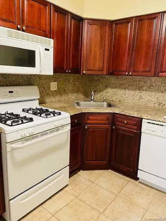 a kitchen with granite countertop wooden cabinets and white appliances