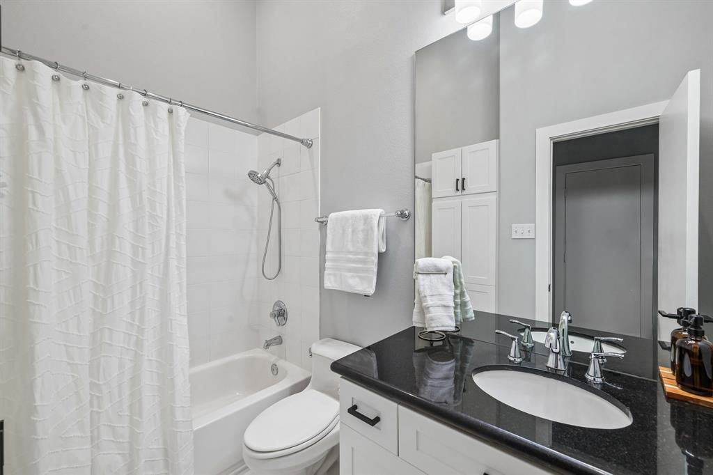 3553 Wheeler Street Dallas, TX 75209 - Photo 21 of 35 Full bathroom with tub-shower combo, black granite vanity countertop, white cabinetry, and large mirror