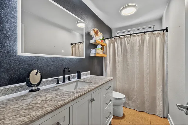 a bathroom with a granite countertop sink toilet and mirror