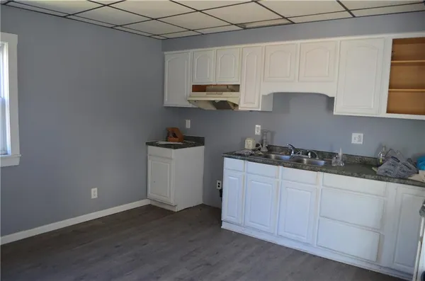 a kitchen with granite countertop white cabinets and a stove top oven
